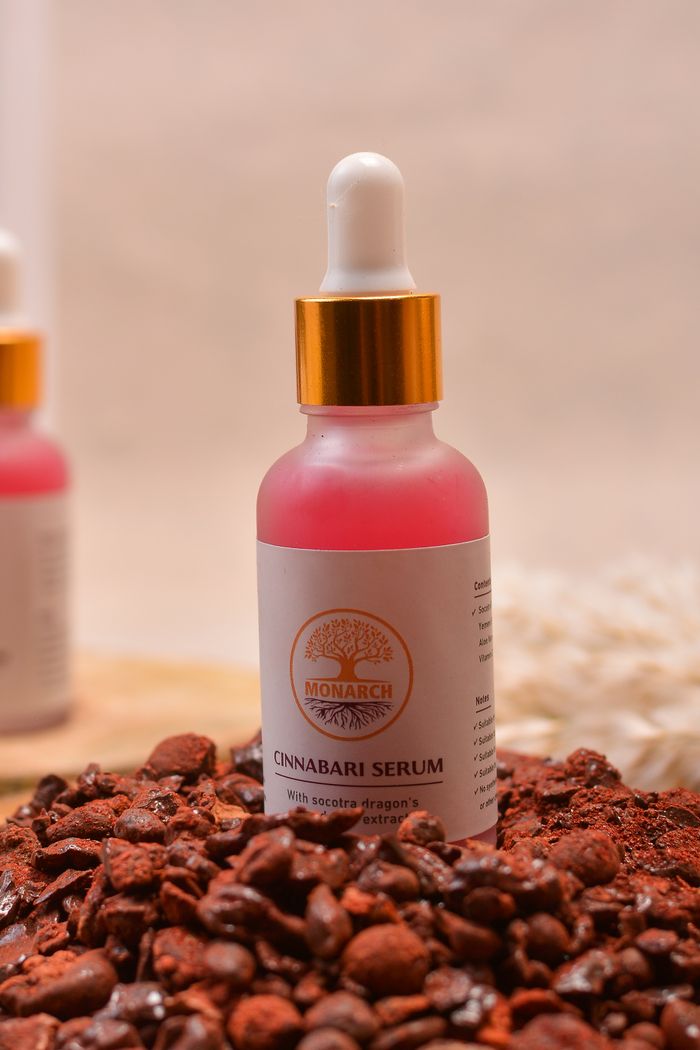 Services-01 Close-up of Cinnabari Serum bottle surrounded by raw cinnabar stones for skincare.